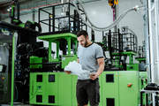 STIHL Tirol Mitarbeiter Adem Navruz mit einem der ersten Teile, die in der neuen Kunststoff-Fertigung in Langkampfen produziert wurden – einem Gehäuseteil für einen Akku-Rasenmäher.
